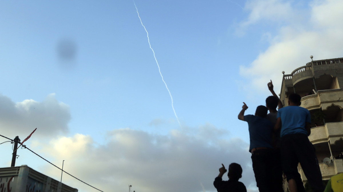 Palestinians at the funeral of a child killed in a Gaza explosion point to the smoke trail of a missile fired by militants from inside northern Gaza Strip on July 28.