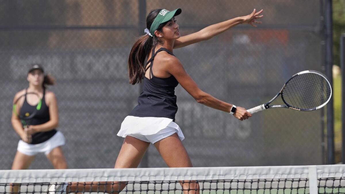 Sage Hill School's Karina Grover, center, scores at the net as partner Miranda deBruyne, left, looks on during a No. 1 doubles set against Mater Dei in a nonleague girls' tennis match on Tuesday.