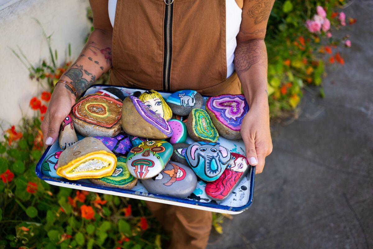 Mary Claire with a tray of her painted rocks in her front yard in Pacific Beach.