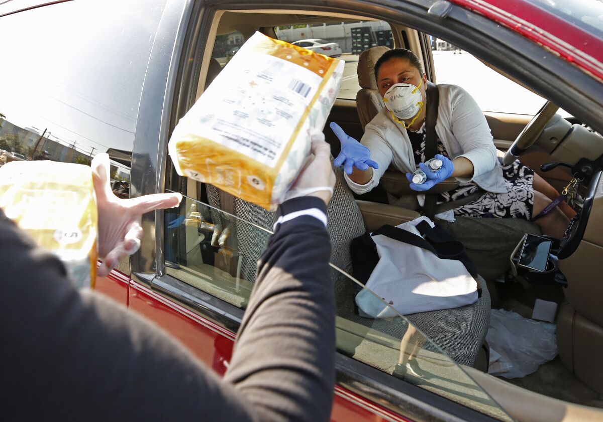 Mary Silva, left, with Pathways LA, hands out diapers and hand sanitizers to Irma Juarez, who has two young children.