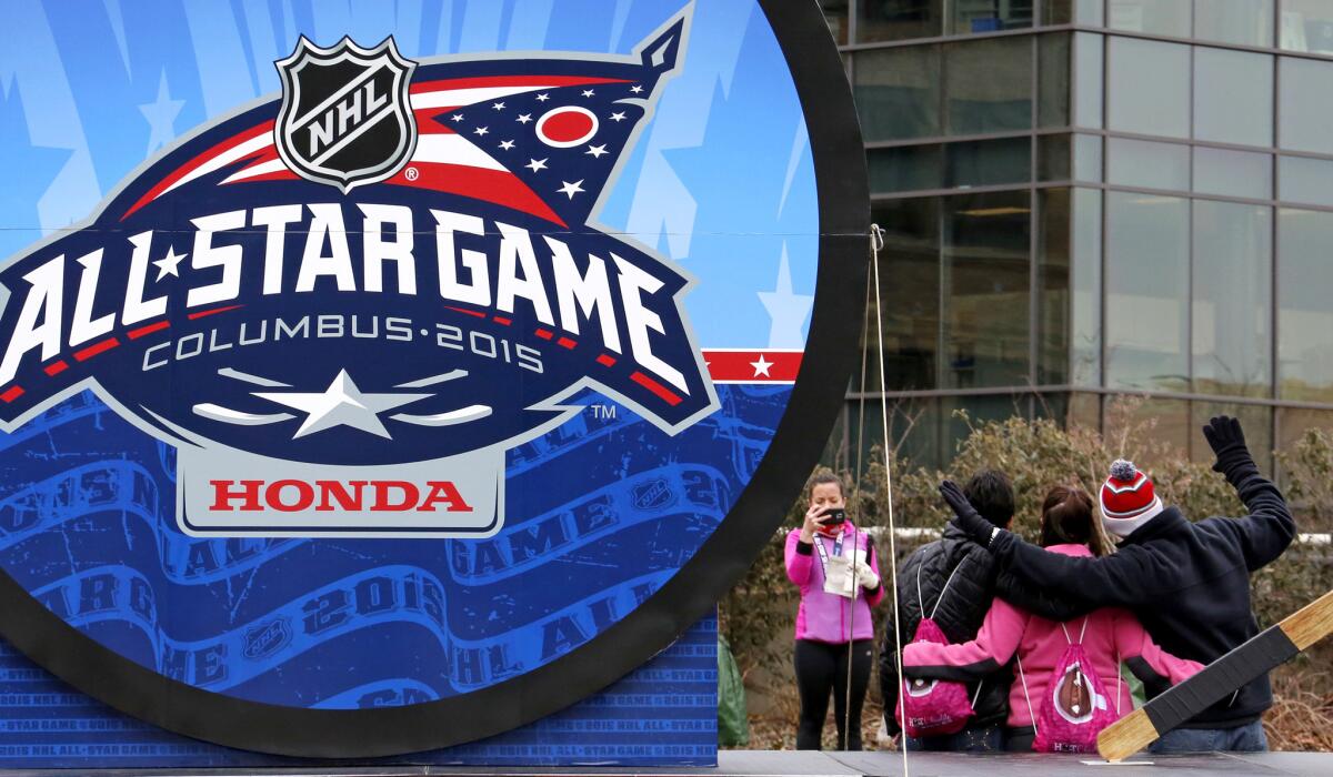 Hockey fans pose near a giant hockey puck outside Nationwide Arena on Saturday in Columbus, Ohio, where the NHL All-Star game will be played Sunday.