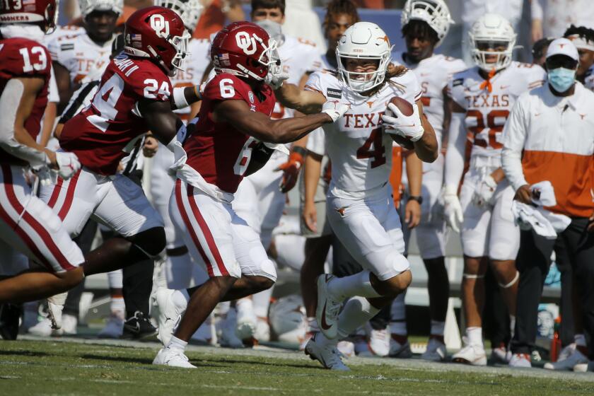Texas wide receiver Jordan Whittington (4) tries to stiff-arm Oklahoma defensive back Tre Brown (6) after a reception during an NCAA college football game in Dallas, Saturday, Oct. 10, 2020. (AP Photo/Michael Ainsworth)
