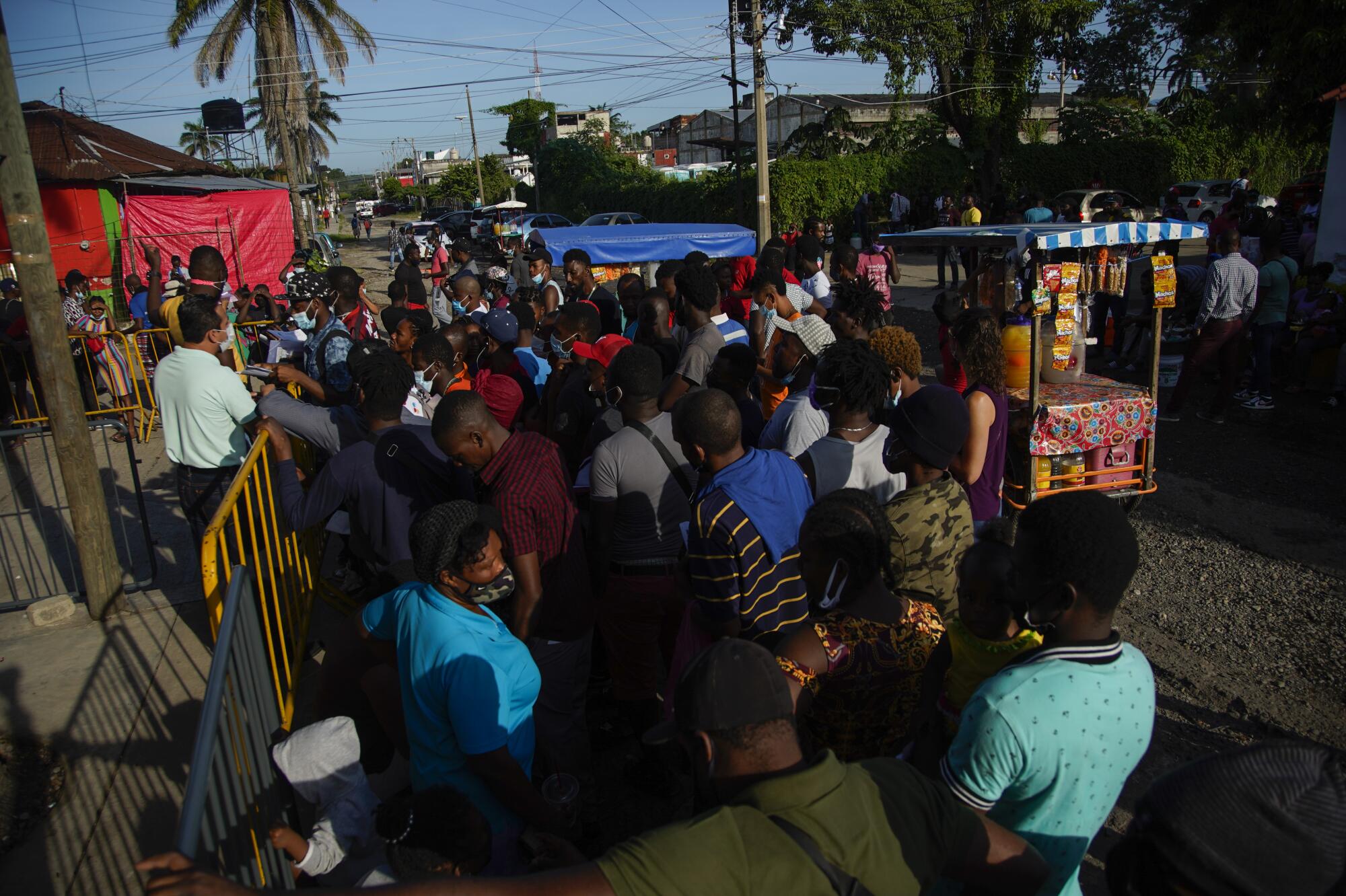 An official takes questions from a group of Haitians waiting outside an asylum office while a Haitian man translates 