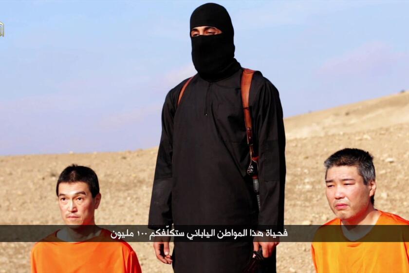 A video purportedly released by Islamic State on Jan. 20 shows Japanese hostages Kenji Goto, left, and Haruna Yukawa with a militant at an undisclosed location.