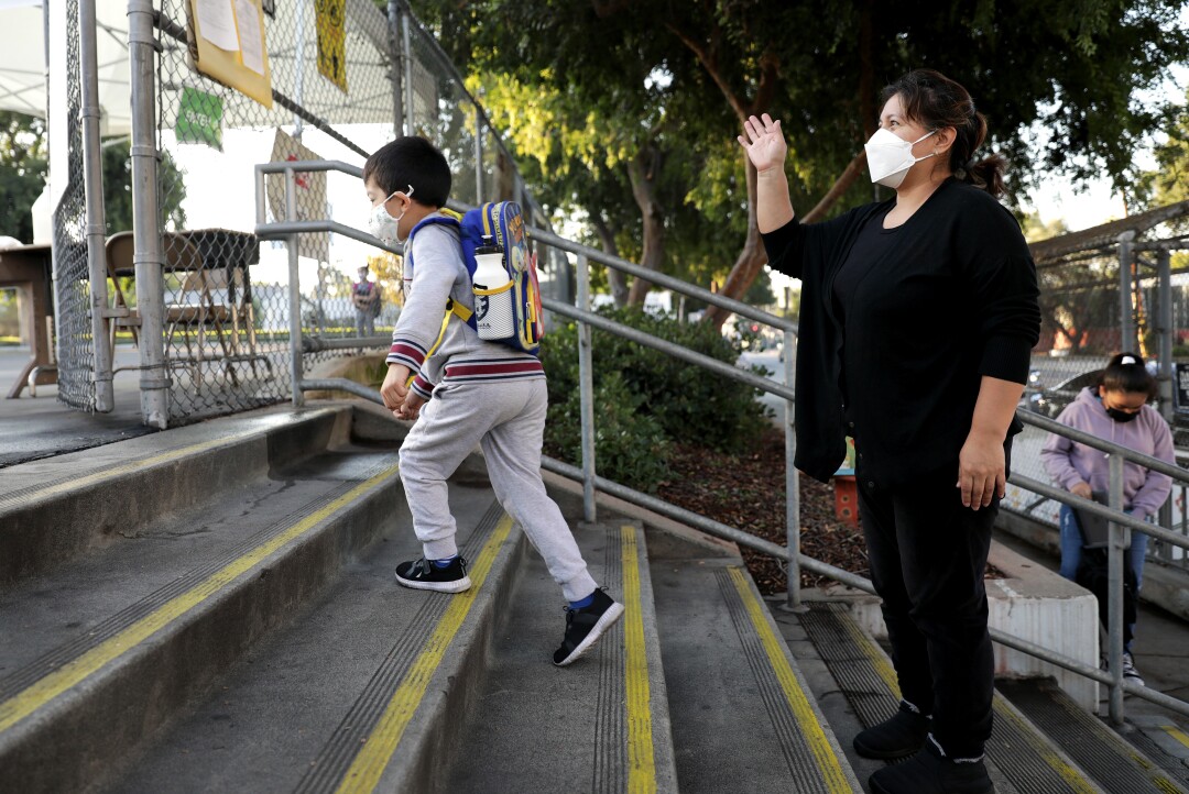 Glenda Valenzuela waves to a school staff member as her son Daniel runs up the steps.