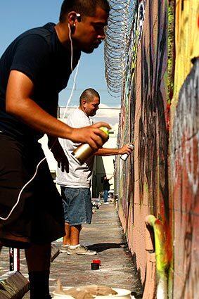Brandon Reyes, 21, left, paints a wall at the Graff Lab, a program offering space for artistic expression at the Pico Union Housing Corp. It aims to transform street taggers into skilled artists. See full story