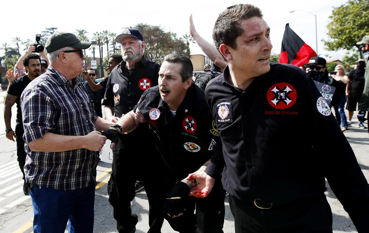 Injured Ku Klux Klansmen flee from angry counter-protesters after they tried to start a "White Lives Matter" rally in Anaheim on Feb. 27.