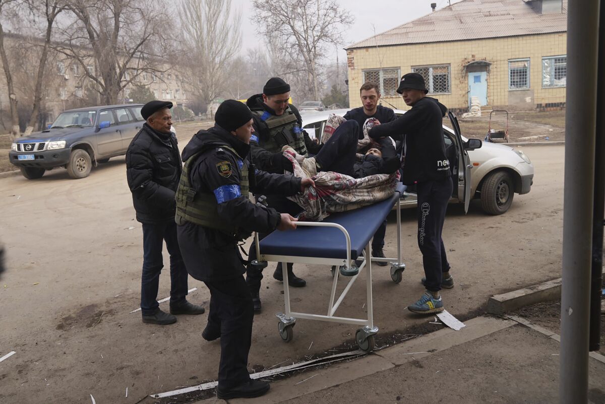 Ukrainian servicemen and volunteers carry a man injured during a shelling attack into hospital number 3 in Mariupol, Ukraine, Tuesday, March 15, 2022. (AP Photo/Evgeniy Maloletka)