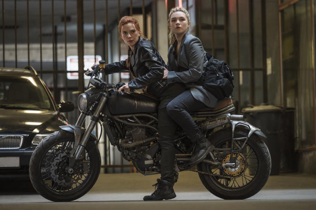 Scarlett Johansson as Black Widow/Natasha Romanoff and Florence Pugh as Yelena Belova sit on the back of a motorcycle