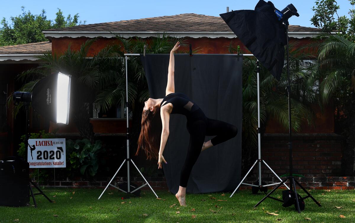 A woman dances in front of a photo backdrop 