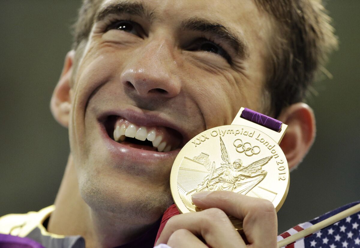 FILE - In this July 31, 2012 file photo, United States' Michael Phelps poses with his gold medal for the men's 4x200-meter freestyle relay swimming final at the Aquatics Centre in the Olympic Park during the 2012 Summer Olympics in London. (AP Photo/Matt Slocum, File)