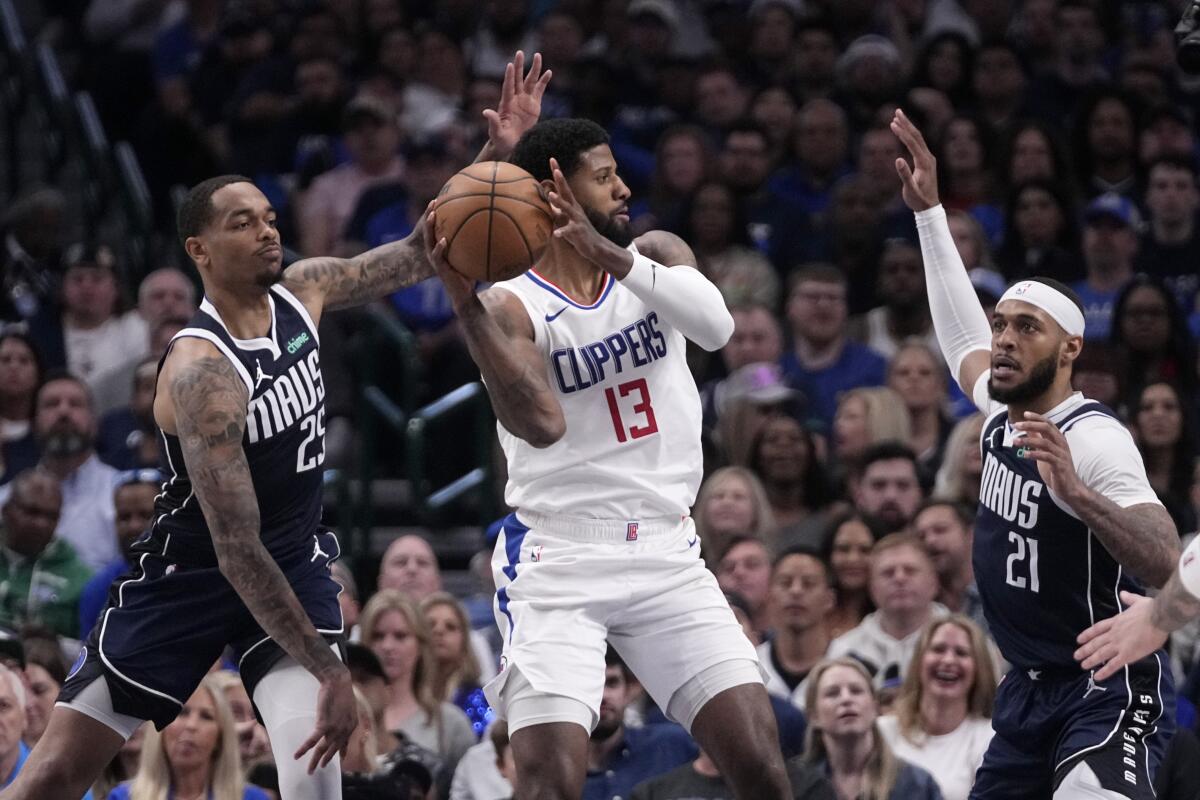 Clippers forward Paul George, center, looks to pass as Dallas' P.J. Washington, left, and Daniel Gafford pressure him.