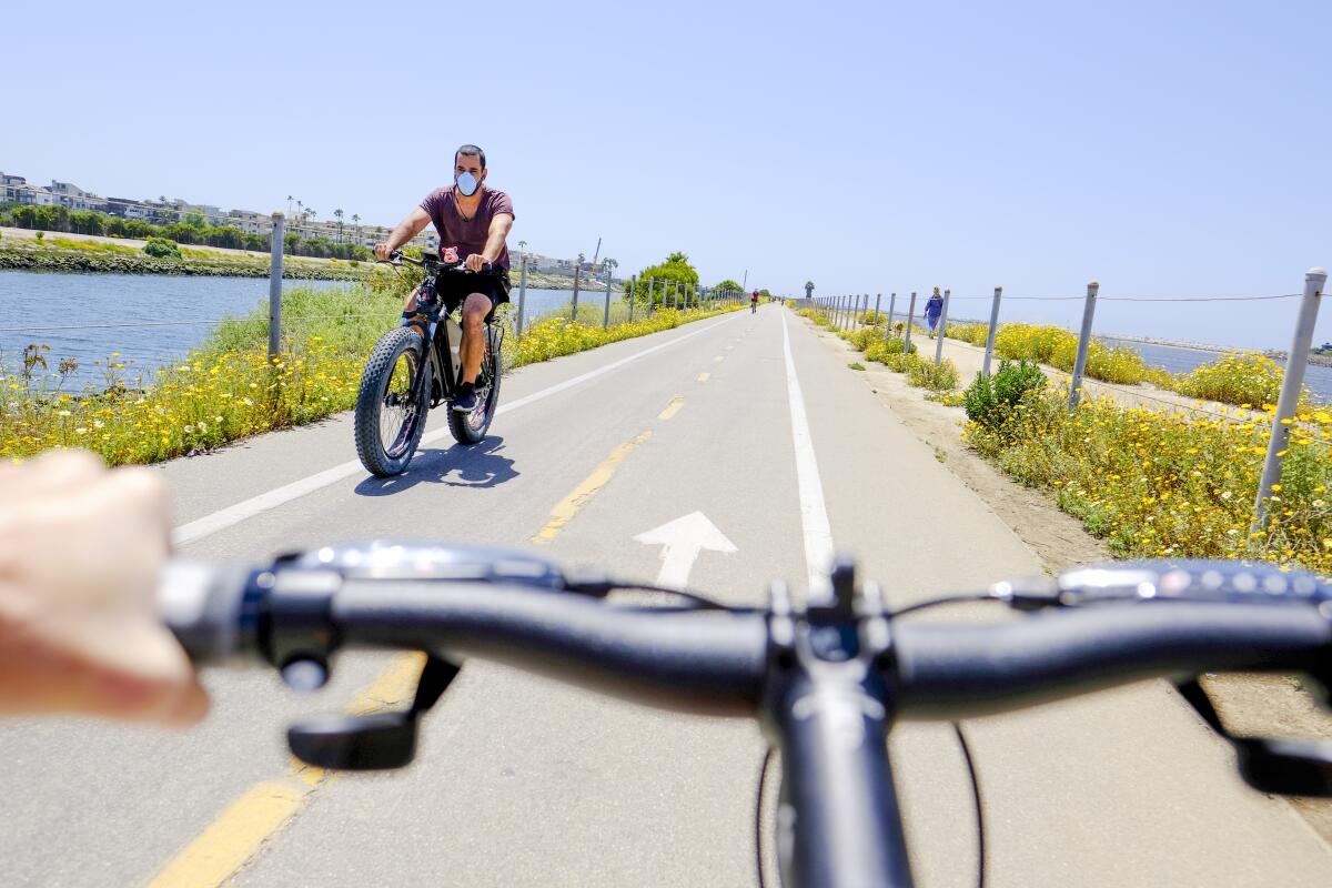 A cyclist with a protective face mask is seen on the Marvin Braude Bike Trail during the coronavirus pandemic on May 04, 2020 in Marina del Rey, California.