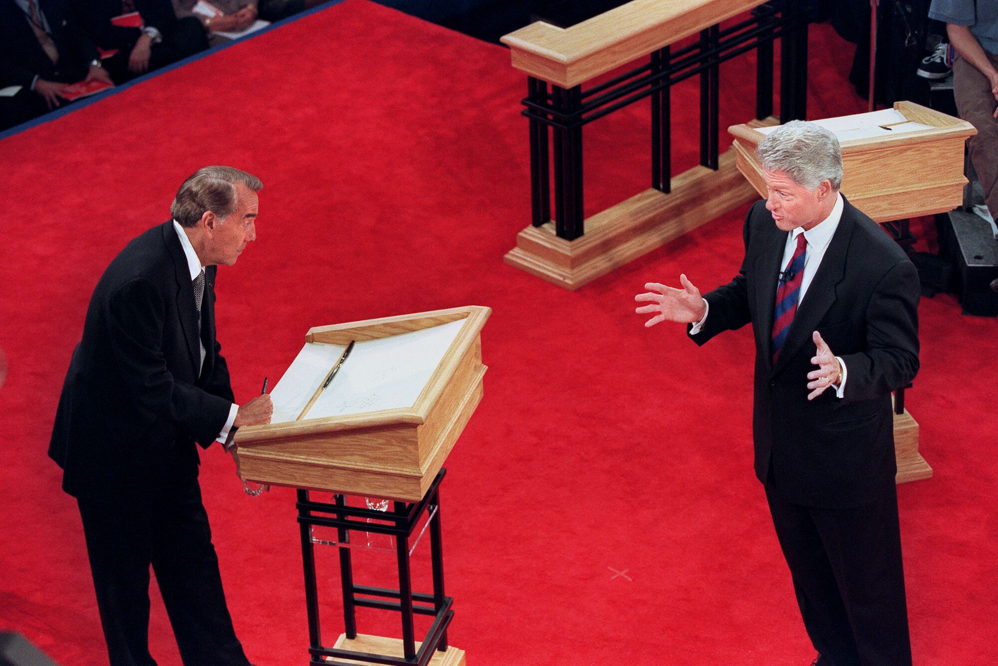 Bill Clinton, right, and Bob Dole, left, stand on a red podium facing each other during a 1996 presidential debate