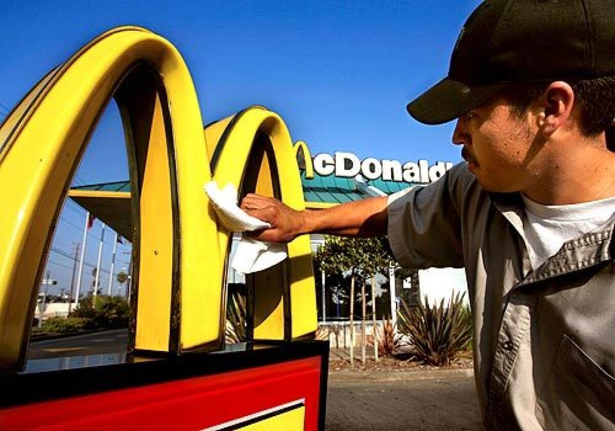 BREADWINNER: Isidro Mata, a 25-year-old McDonald's maintenance worker, polishes a sign at one of the chain's Los Angeles restaurants. Much of the money he earns he sends home to relatives in Mexico.