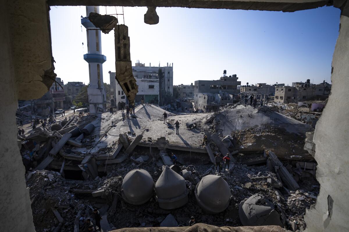 Palestinians look at the destruction after an Israeli strike on residential buildings and a mosque in Rafah, Gaza Strip.