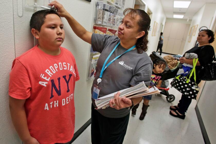 FONTANA, CA - OCTOBER 01, 2013 --- Nurse Marisol Vasquez measures the height of 11-year-old Victor Garcia who was at Molina Health Clinic with his mother Marisela Garcia, 27, extreme, right, and his two other siblings. Garcia have Medi-Cal but she just got married and will no longer qualify for Med-Cal. She came into the clinic in Fontana looking to purchase insurance through the exchanges, because her insurance is expiring at the end of November. (Irfan Khan / Los Angeles Times)