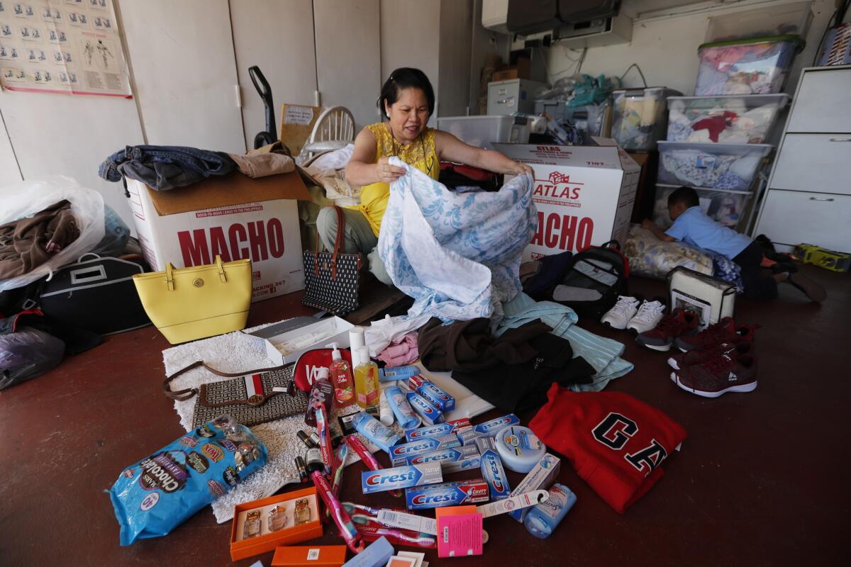 Amy Guzman, who will be visiting her family in the Philippines, packs two balikbayan boxes full of things such as toothpaste, Spam, hand-me down clothes and rice at her home in Long Beach.