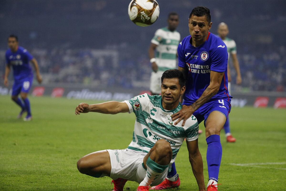 Santos Laguna's Eduardo Aguirre, bottom, and Cruz Azul's Julio Dominguez compete for the ball 