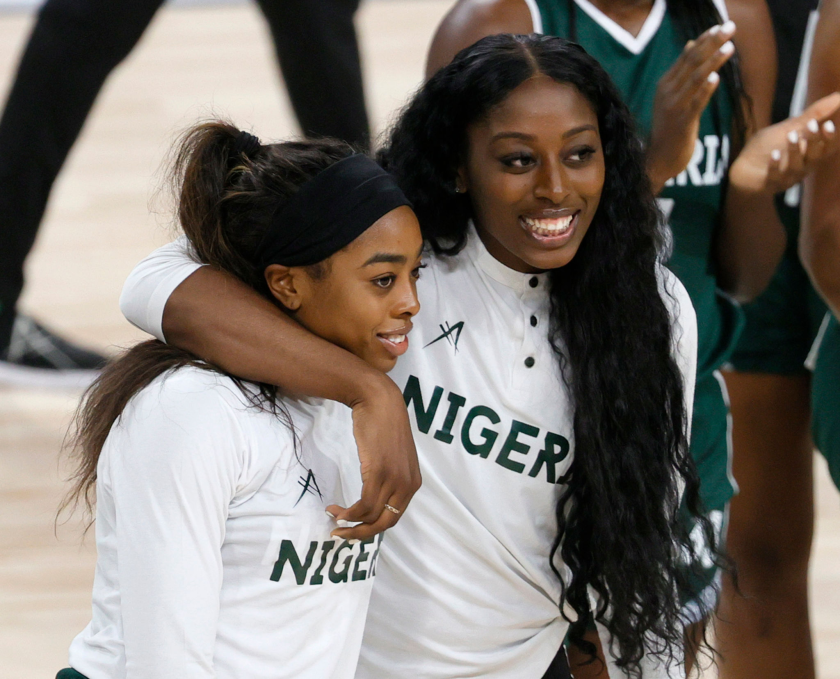 Erica Ogwumike and sister Chiney Ogwumike smile on the court while Chiney has her arm around Erica's neck