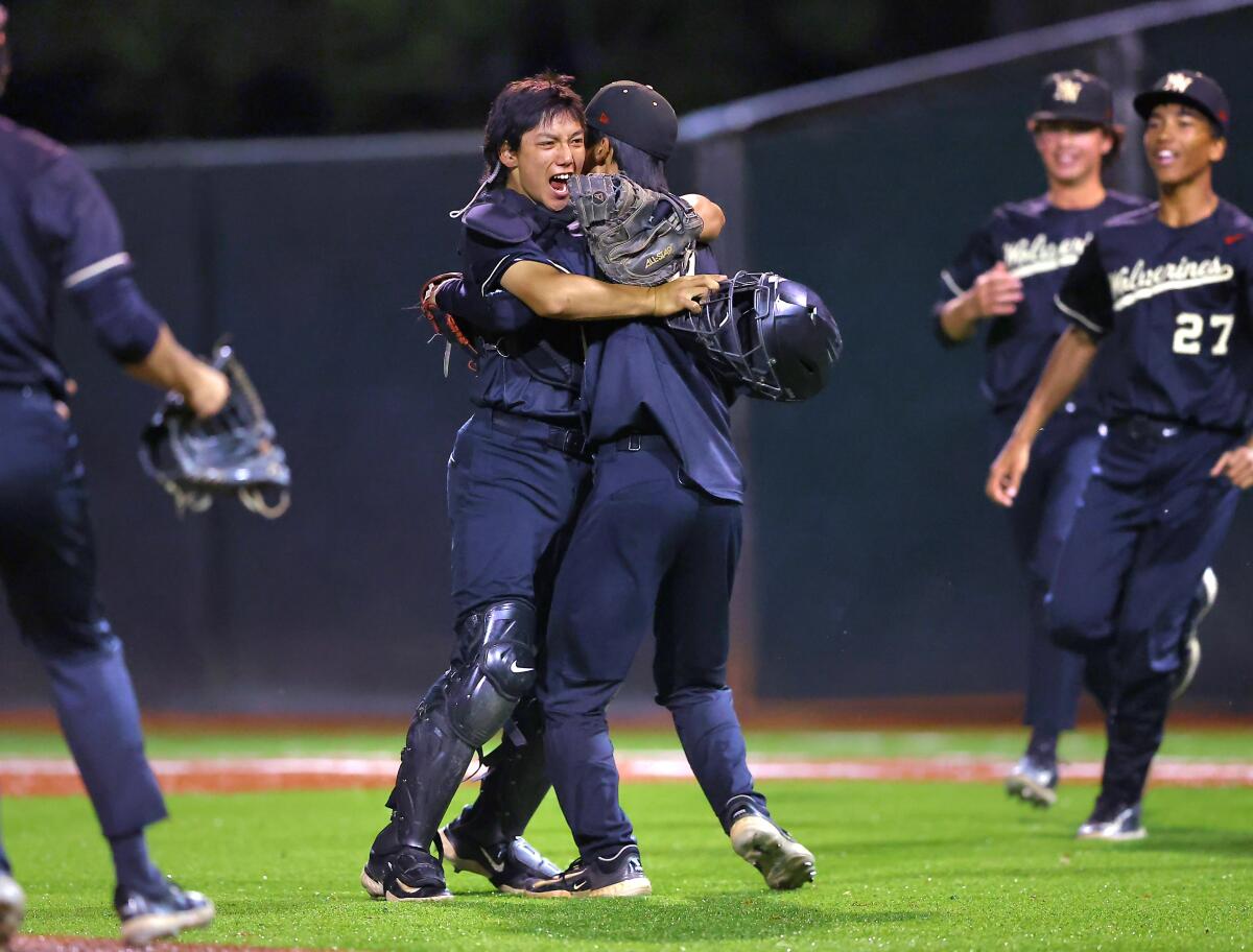 Catcher Nate Blum embracing relief pitcher Jake Chung as teammates rush in on a baseball diamond