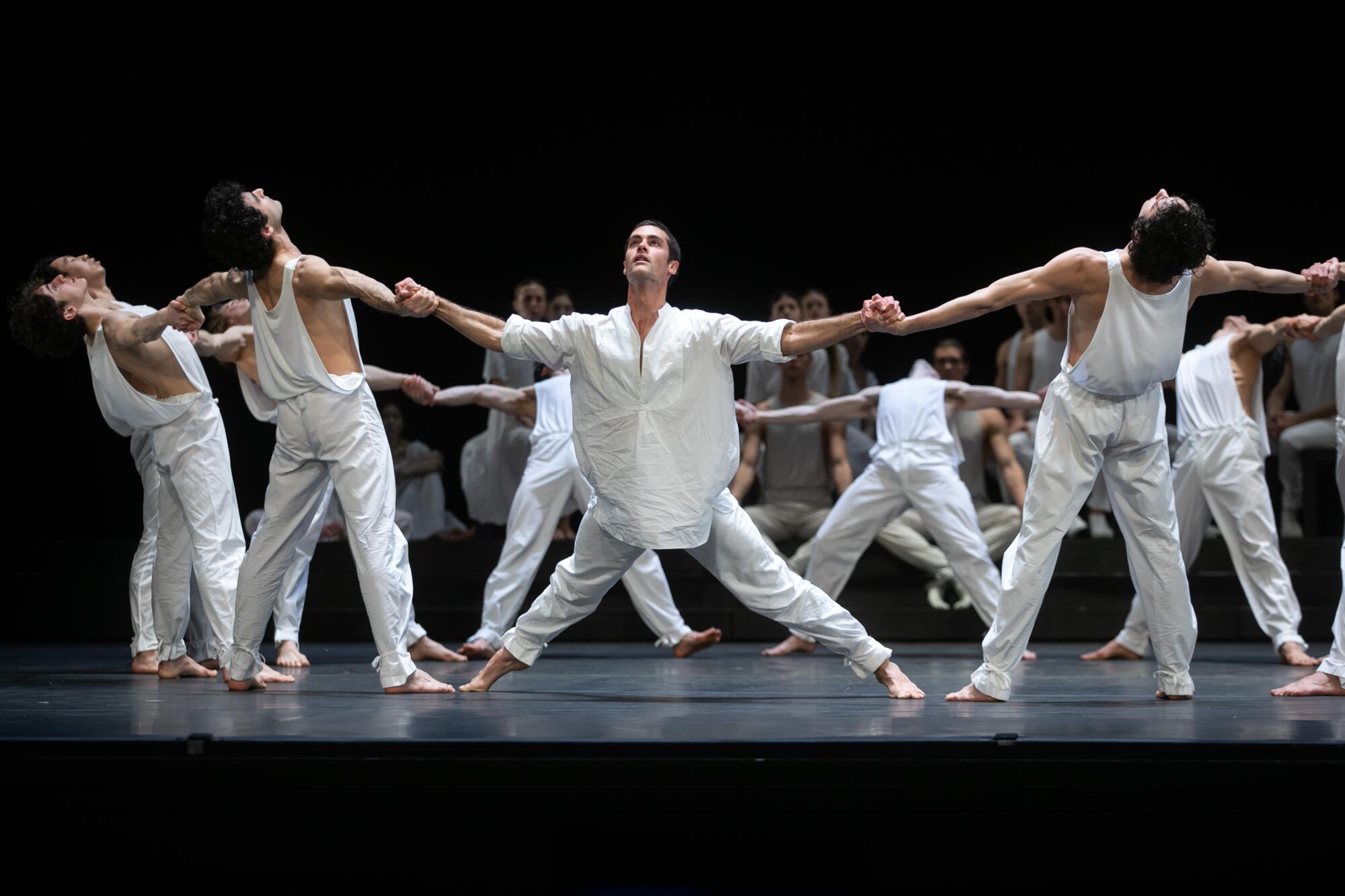 Standing in a circle, dancers link hands and lean outward.