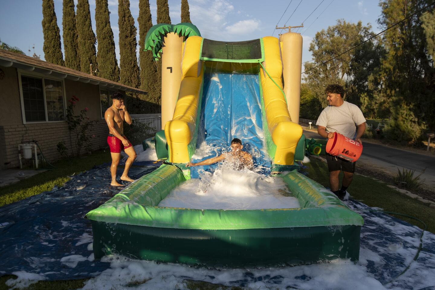 Teens cavort on a backyard waterslide in Mira Loma.