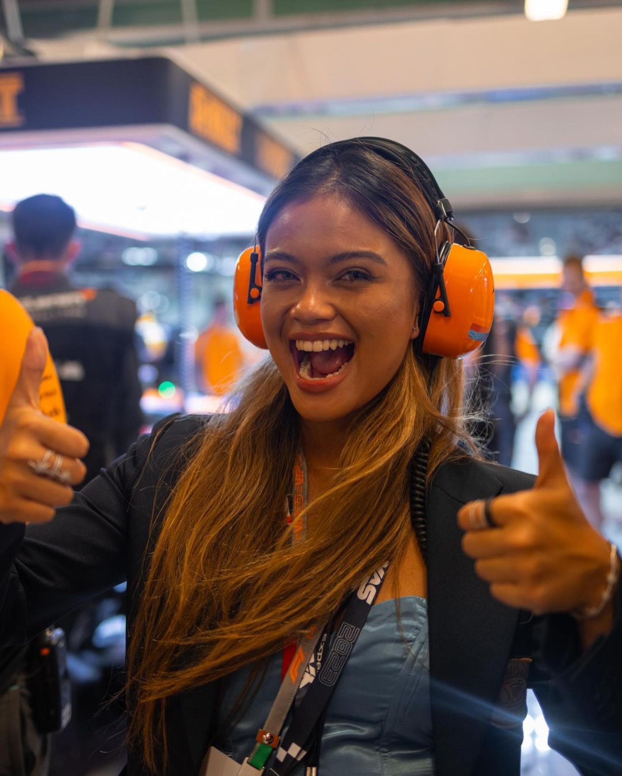 Bianca Bustamante gives a thumbs up while standing in the McLaren garage during a Formula One race weekend.