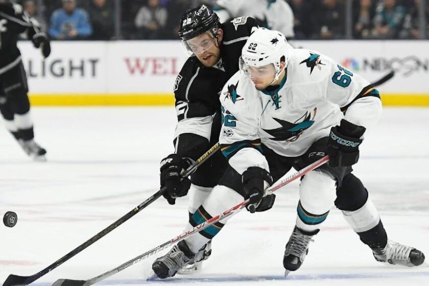 Kings forward Trevor Lewis and San Jose forward Kevin Labanc battle for the puck during the first period of a game at Staples Center on Jan. 18.
