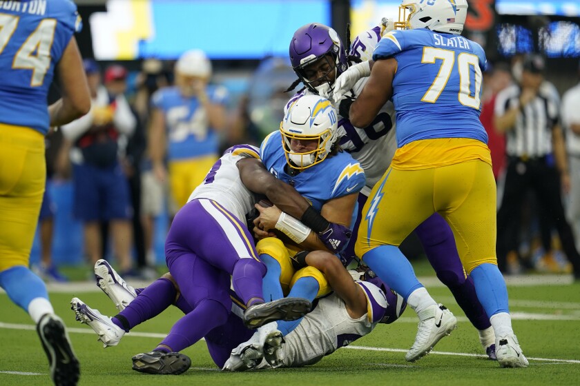 Chargers quarterback Justin Herbert (10) is sacked by Vikings safety Camryn Bynum.