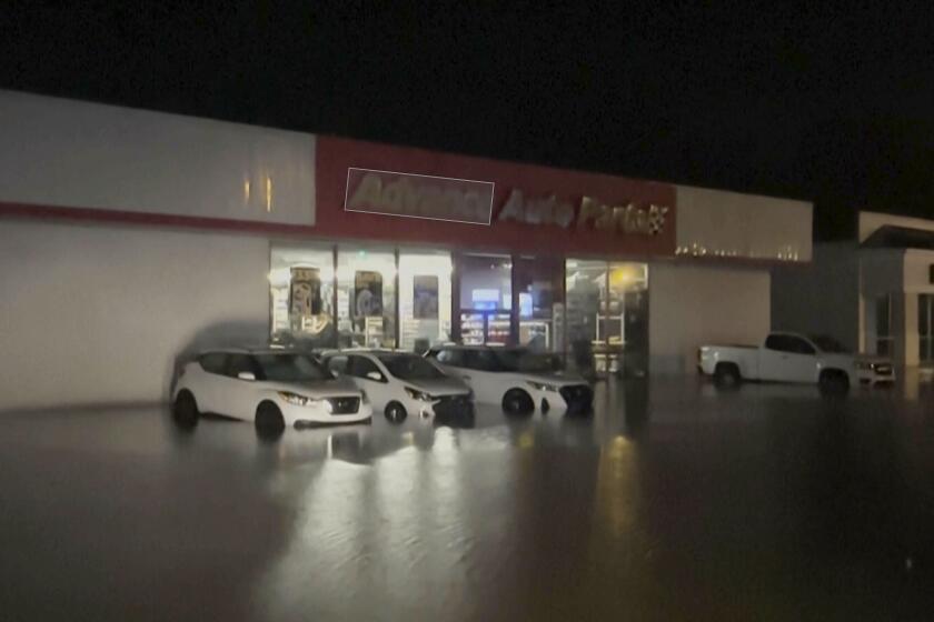 Inundaciones repentinas rodean autos estacionados afuera de una tienda Moncks Corner, Carolina del Sur, tras el paso de la tormenta tropical Debby, el viernes 9 de agosto de 2024. (WCBD vía AP)