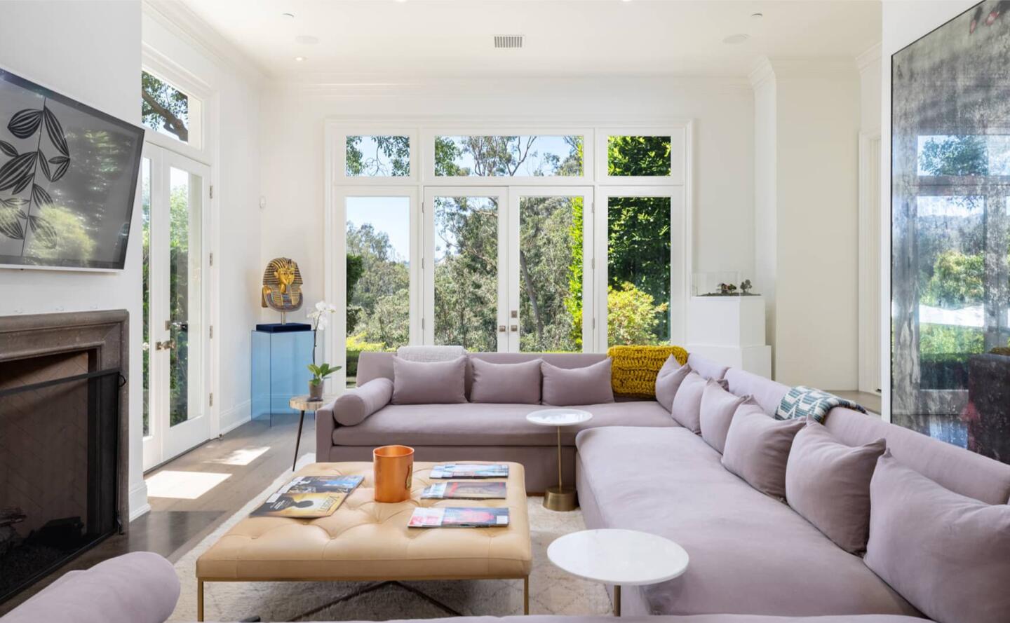 The living room is furnished and has windows overlooking greenery.