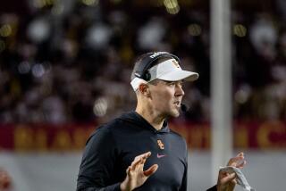 USC coach Lincoln Riley holds up both hands and calls a play from the sidelines during a game 