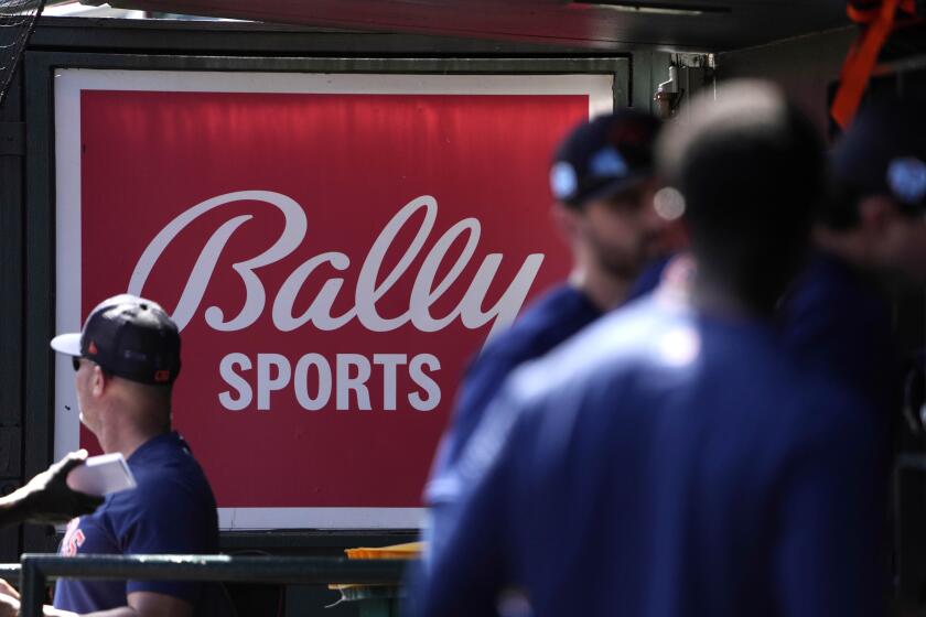 FILE -A Bally Sports sign hangs in a dugout before the start of a spring training baseball game between the St. Louis Cardinals and Houston Astros Thursday, March 2, 2023, in Jupiter, Fla. Comcast has blacked out 15 regional sports networks offered by Bally Sports, escalating a contract dispute with their distributor. The cutoff that began Wednesday, May 1, 2024 affects games played by a dozen Major League Baseball teams based in nine states. (AP Photo/Jeff Roberson, File)