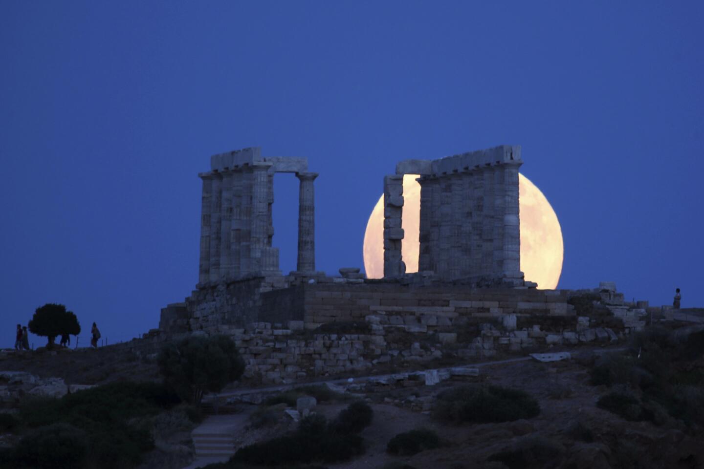 A full moon rises behind the ancient temple of Poseidon in cape Sounio, south of Athens. The complete lunar eclipse Friday when the sun, Earth and moon line up perfectly to cast Earth's shadow on the moon, will be the longest this century. It's called a "blood moon" because it turns a deep red and will be visible at different times around the world.