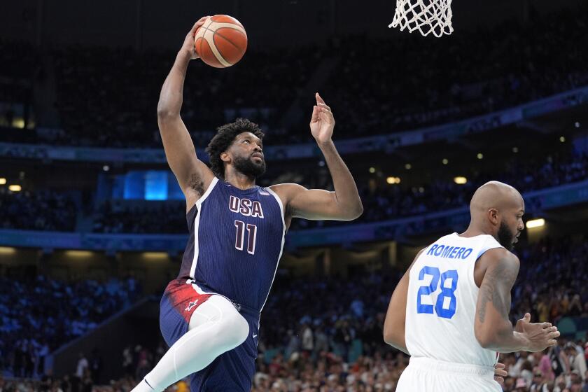 El estadounidense Joel Embiid clava el balón ante el puertorriqueño Ismael Romero en el baloncesto de los Juegos Olímpicos de París, el sábado 3 de agosto de 2024, en Villeneuve-d'Ascq, Francia. (AP Foto/Michael Conroy)