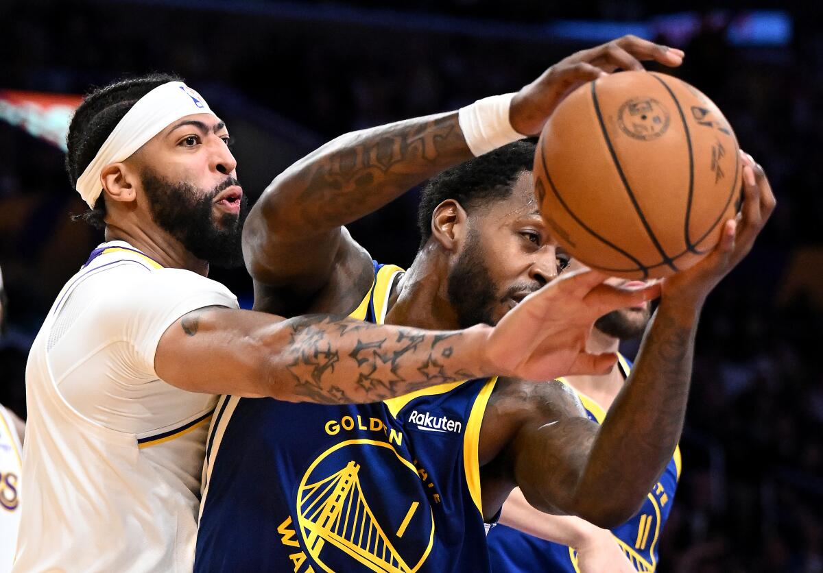 Lakers forward Anthony Davis reaches under the right arm of Warriors forward JaMychal Green to strip the ball from his grip.