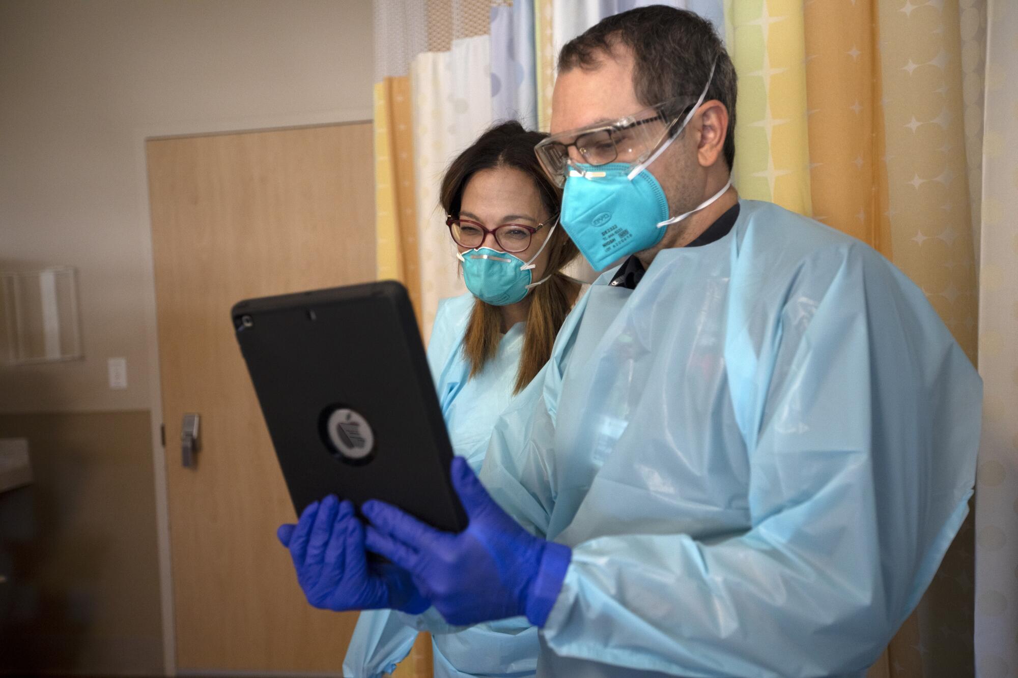 Dr. Marwa Kilani and Chaplain Kevin Deegan look at an iPad.