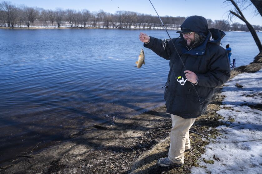 Tyler Abayare catches a red horse carp on the Mississippi River at the Montissippi County Park downriver from the Xcel Energy nuclear power plant in Monticello, Minn., on Friday, March 24, 2023. Abayare fishes at this spot everyday and noticed increased activity including people taking water samples around three times a week in the last 60 days. (Renee Jones Schneider/Star Tribune via AP)
