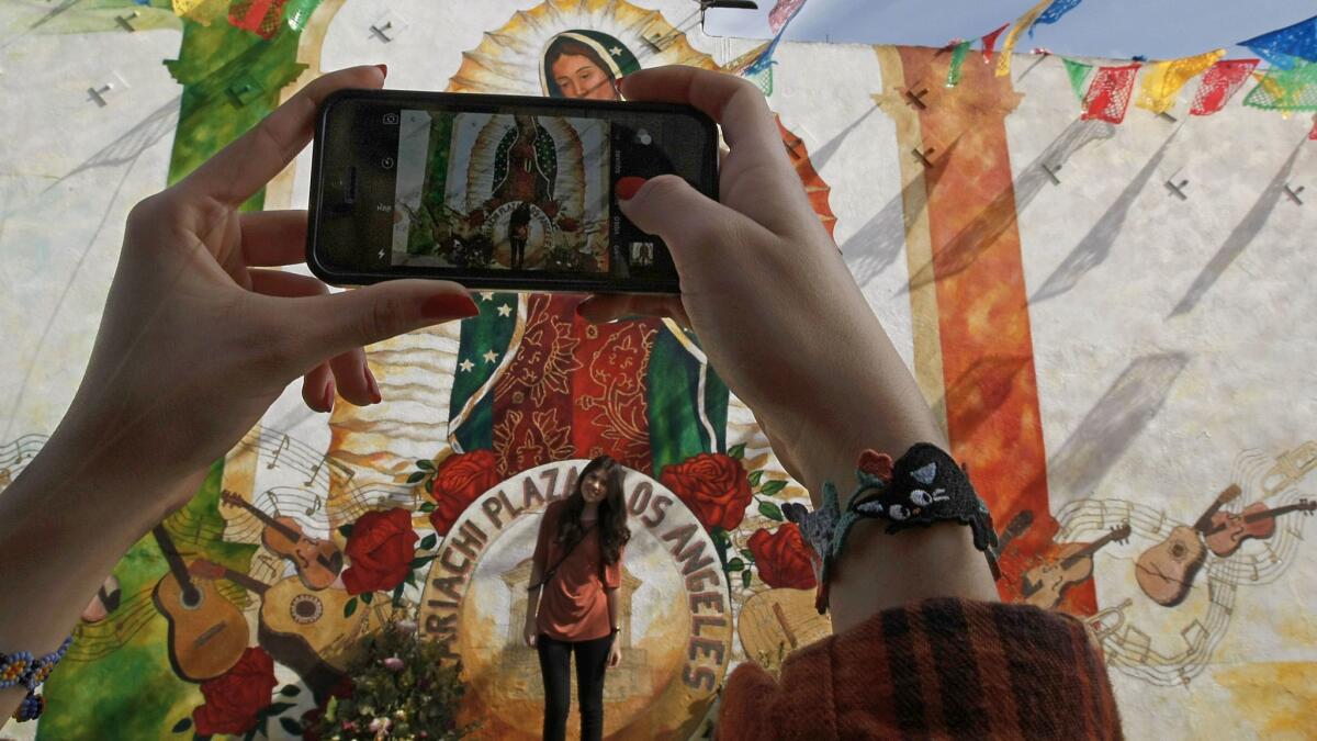 Jessica Alvarez takes a photo of Briana Alvarez on a visit to Mariachi Plaza in Boyle Heights. (Luis Sinco / Los Angeles Times)