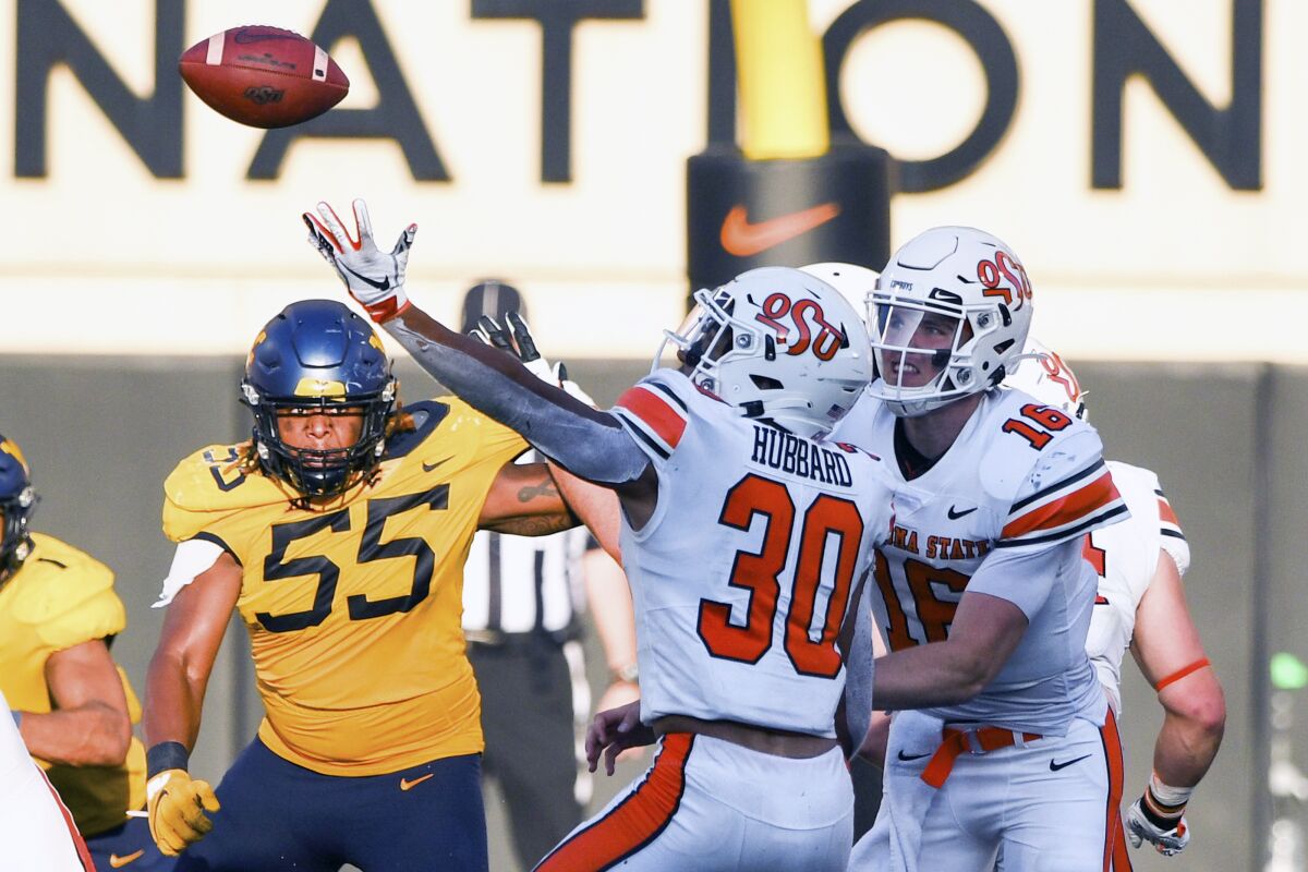 West Virginia defensive lineman Dante Stills (55) and Oklahoma State quarterback Shane Illingworth (16) watch as Oklahoma State running back Chuba Hubbard (30) tries to catch a bad snap during an NCAA college football game Saturday, Sept. 26, 2020, in Stillwater, Okla. (AP Photo/Brody Schmidt)