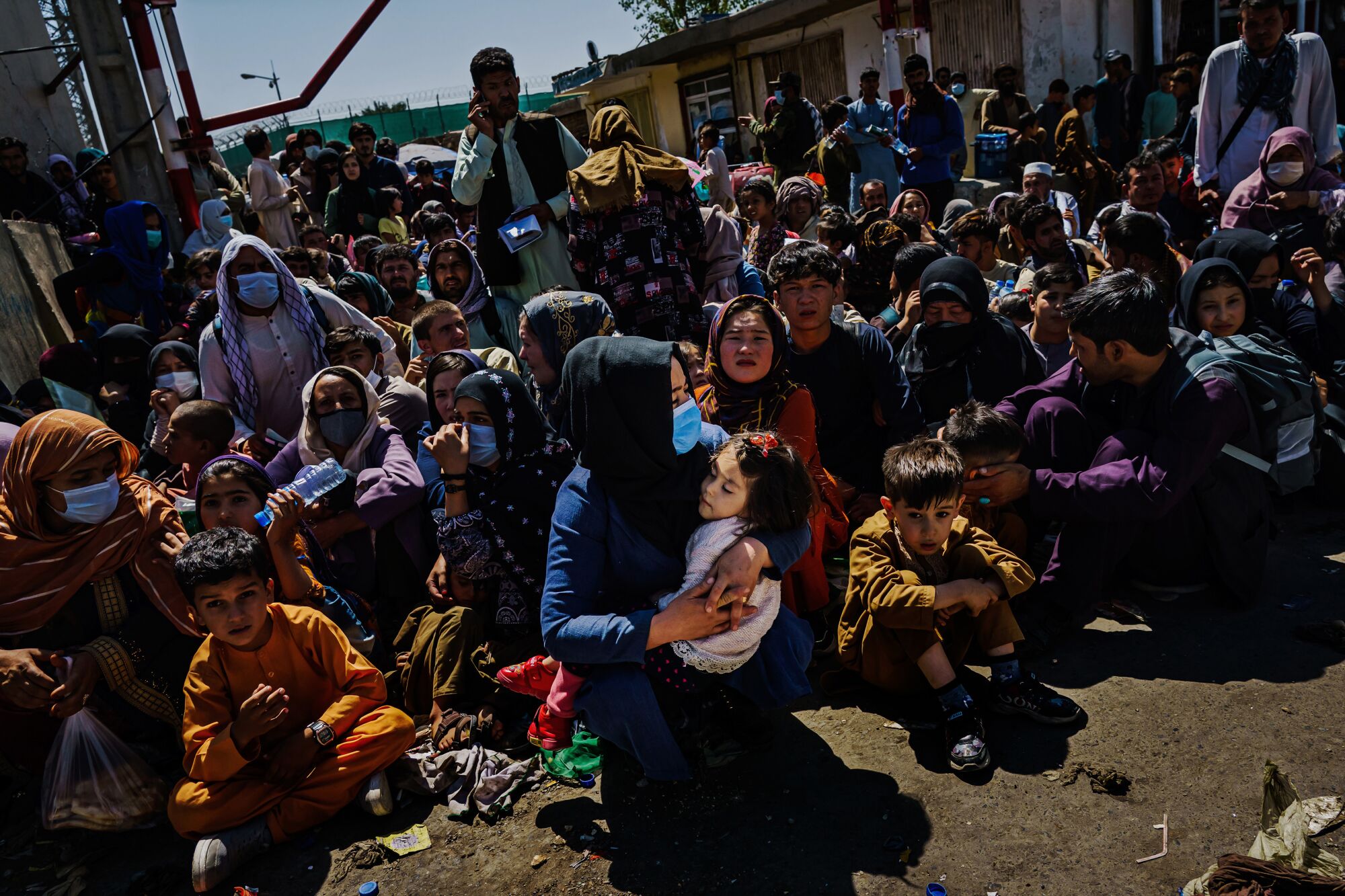 Women and children crouch in the sweltering heat at a Taliban-controlled checkpoint near Abbey Gate