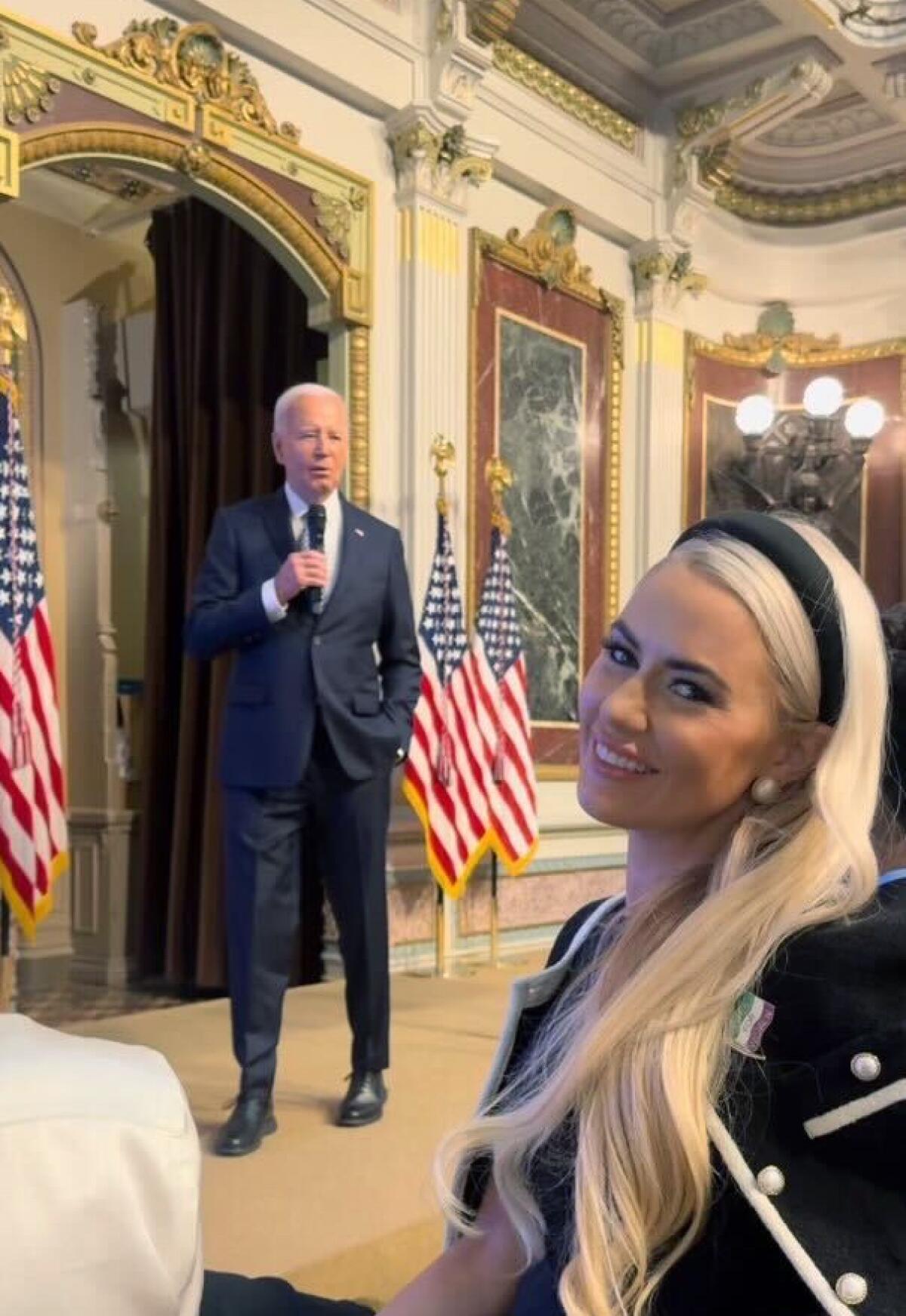 Impresionante Lauren Pietra en primer plano con el presidente Biden hablando de fondo.