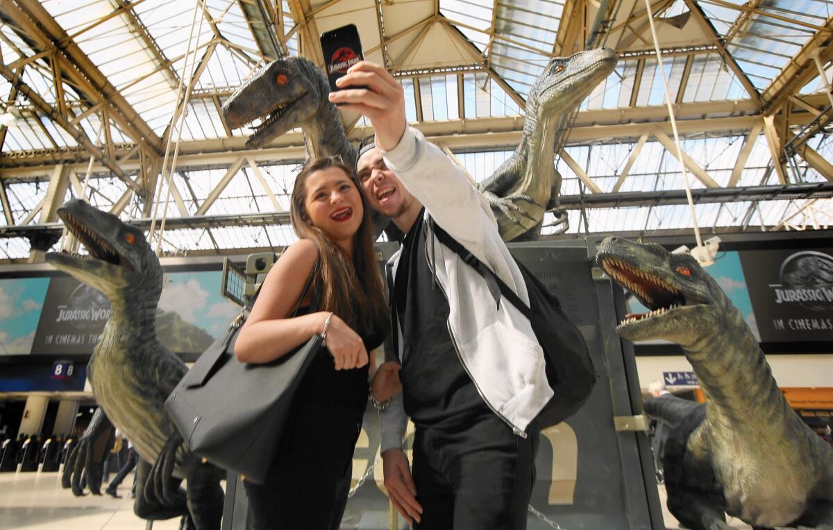 This weekend, the movie “Jurassic World” scored the biggest opening of all time with $524 million in tickets sold worldwide. Above, commuters stop to take a selfie with model raptors as part of a "Jurassic World" exhibition in central London last week before the film's release.