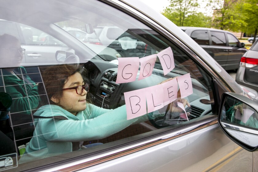 FILE - In this May 5, 2020, file photo, Elizabeth Ruiz, 7, puts up post-it notes on her mother's car window that spell out "God Bless U" as she and her mother Daylin Lemus, of Adelphi, Md., wait in a line of hundreds of cars to receive a Catholic Charities distribution of food at Northwestern High School, in Hyattsville, Md. The Department of Agriculture is sending $1 billion to the country’s food bank networks, seeking to expand the reach of the system and revamp the way food banks acquire and distribute aid. (AP Photo/Jacquelyn Martin, File)