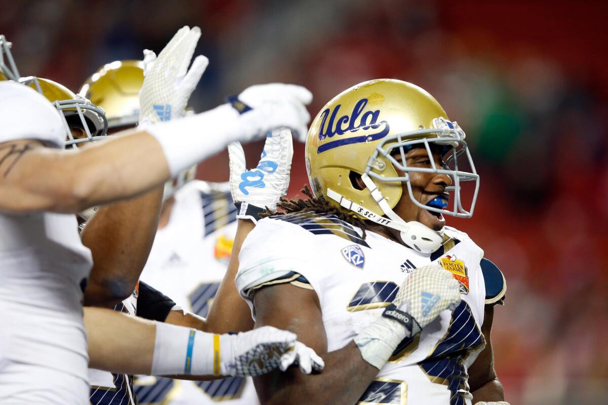 UCLA running back Paul Perkins is congratulated by teammates after scoring a touchdown against Nebraska during the Foster Farms Bowl.