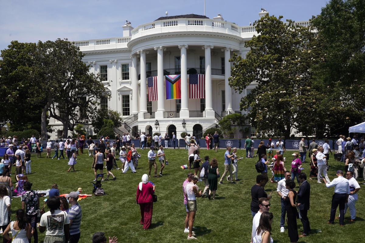 People walk on the South Lawn of the White House during a Pride Month celebration.