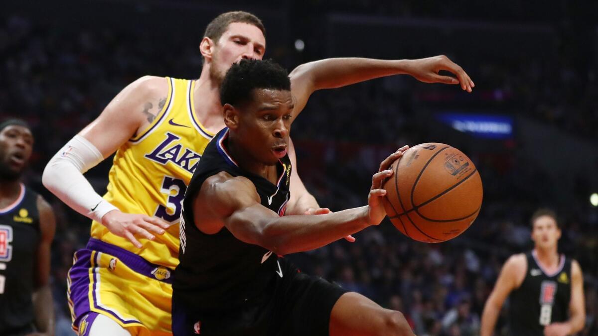 Shai Gilgeous-Alexander of the Clippers saves an outbound ball against Mike Muscala of the Lakers during the second half at Staples Center.