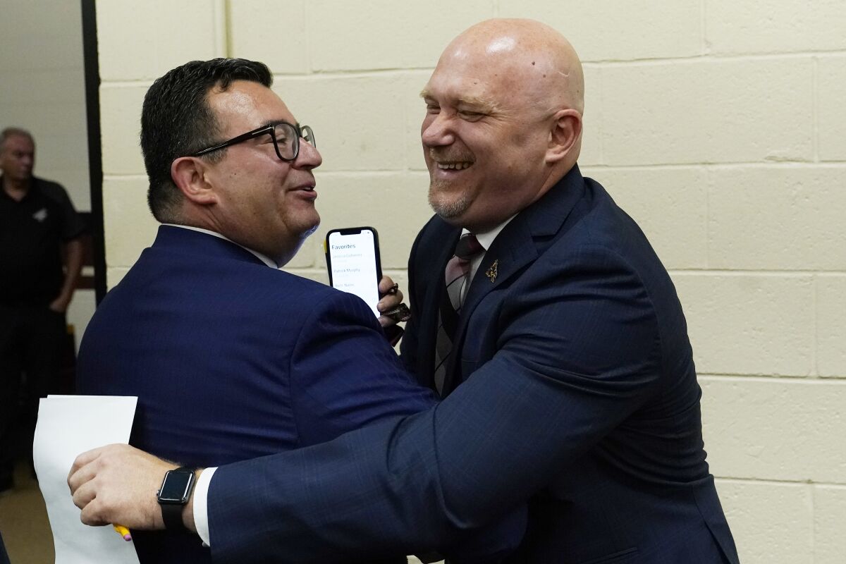 FILE - Arizona Coyotes NHL hockey team president and CEO Xavier Gutierrez, left, greets new team head coach Andre Tourigny, right, after a news conference at Gila River Arena Thursday, July 1, 2021, in Glendale, Ariz. After an eight-hour meeting, the Coyotes finally got what they wanted: approval to negotiate with the city of Tempe to build a new arena close to downtown. (AP Photo/Ross D. Franklin, File)