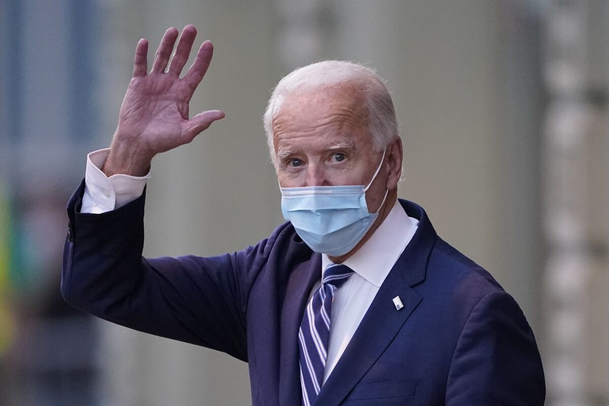 El presidente electo Joe Biden saluda mientras sale del teatro The Queen,